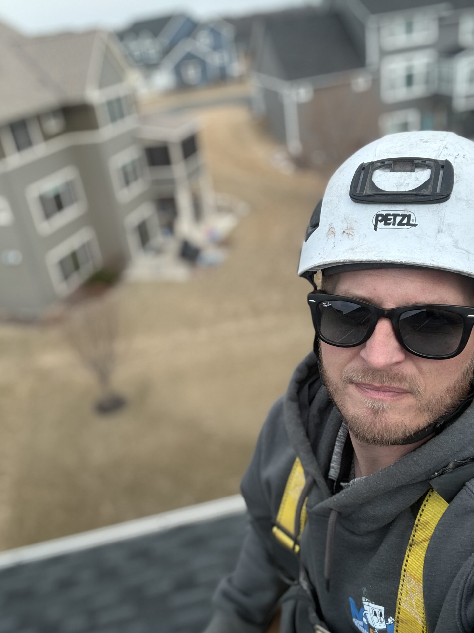The owner, Jason, on a rooftop for a dryer vent cleaning and dryer jack installation. Equipped with a climbing helmet and a rope and harness.